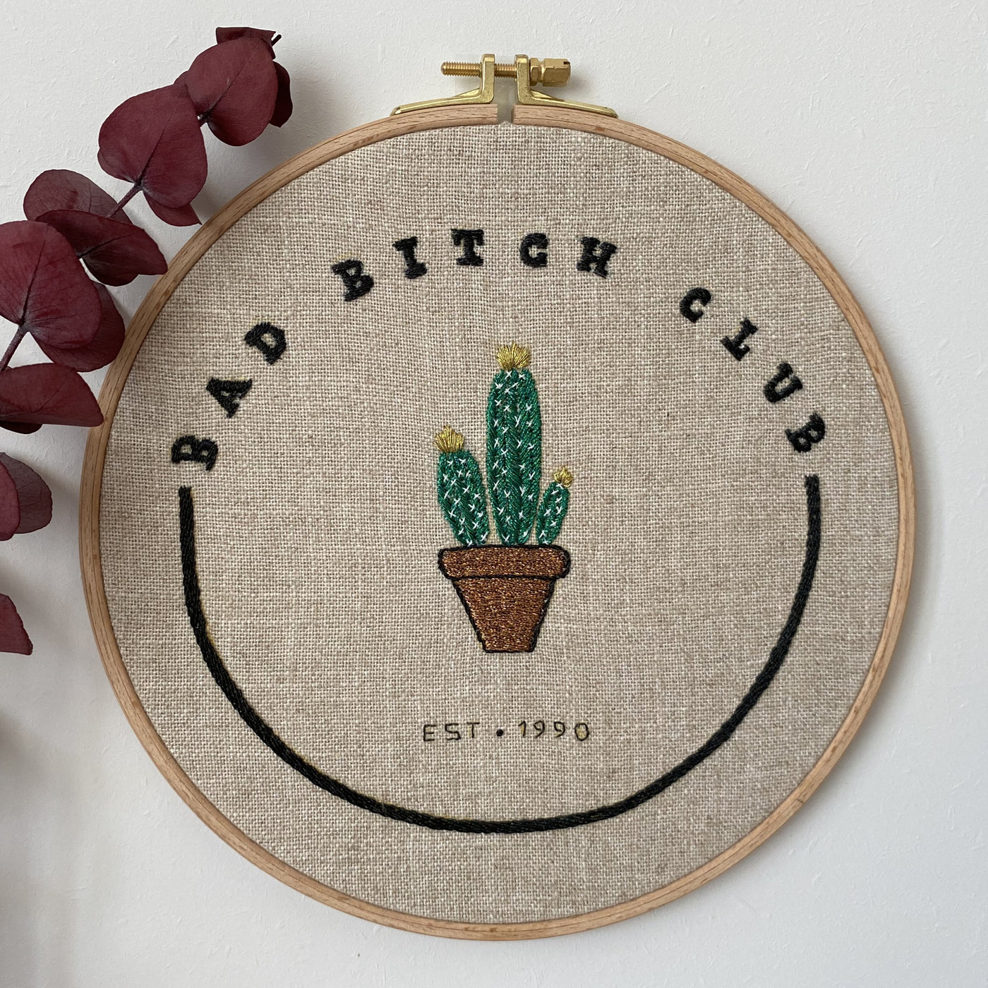 Bad Bitch Club cactus hand embroidery in a wooden hoop on natural linen, with dried eucalyptus