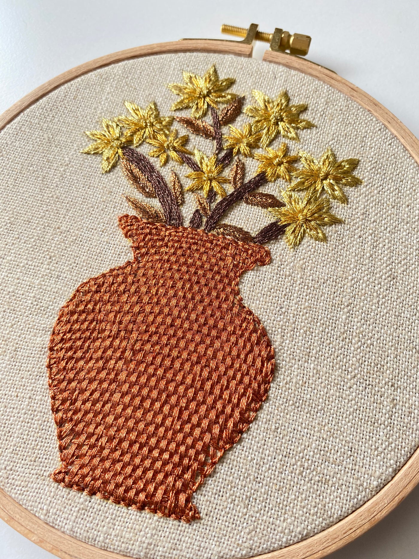 The terracotta vase hoop upright on a stand, golden blooms rising from the rust-coloured vase