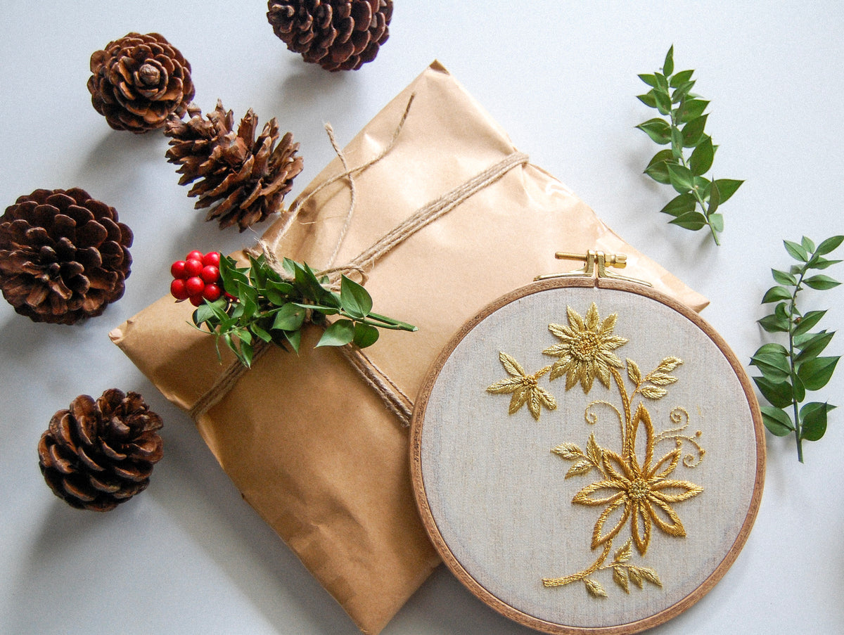 The gilded daisy spray hoop with a wrapped parcel, pine cones and holly berries