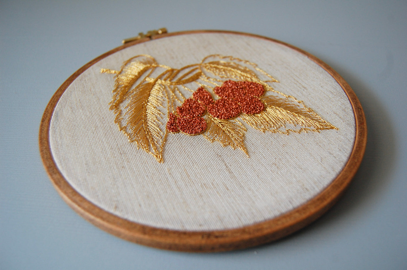 The golden leaves and red berries hoop laid on a pale blue surface