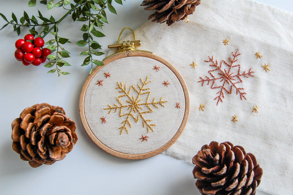 The golden snowflake hoop on white cloth with pine cones and red berries