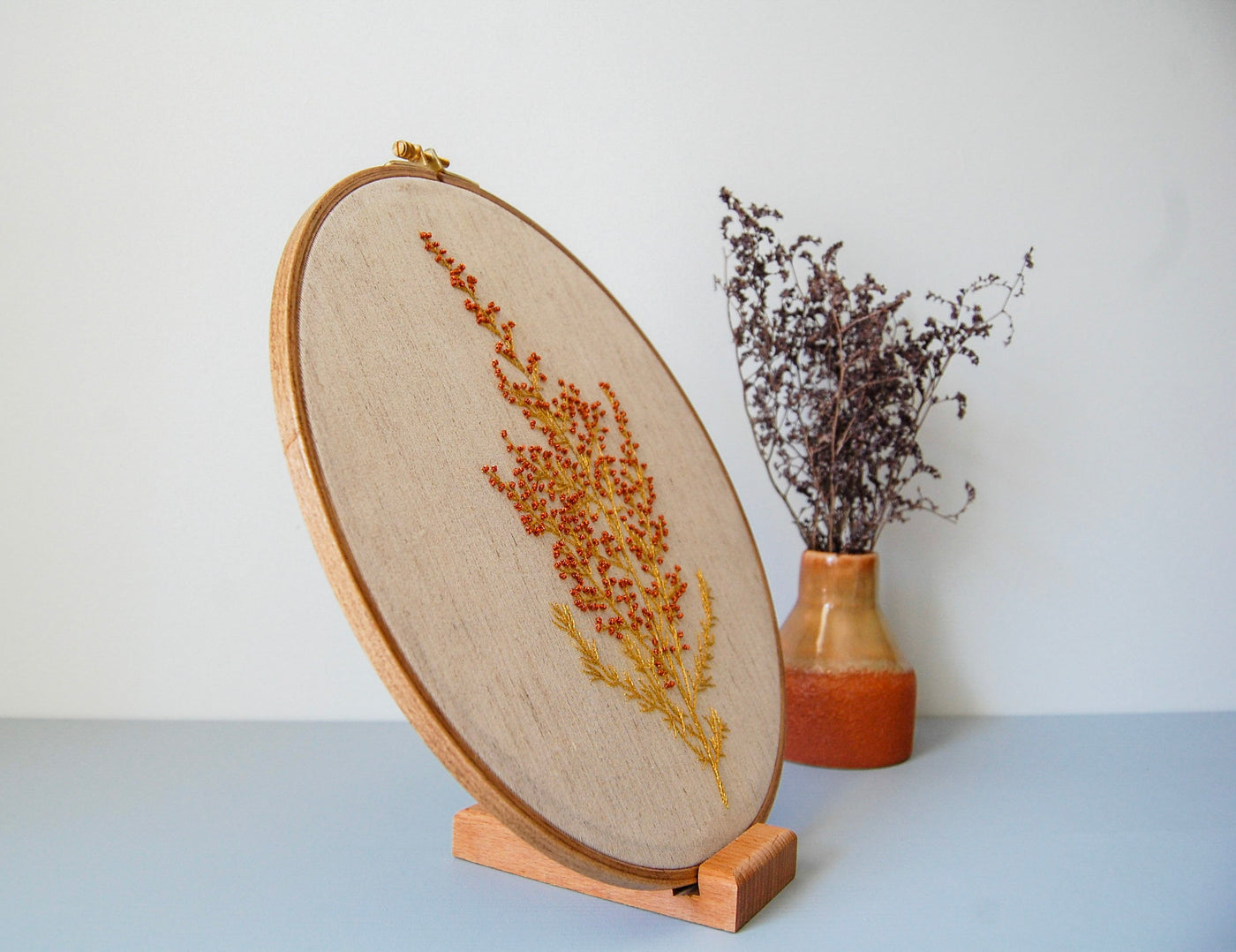 The wildflower spray hoop seen at an angle beside dried lavender in a terracotta vase