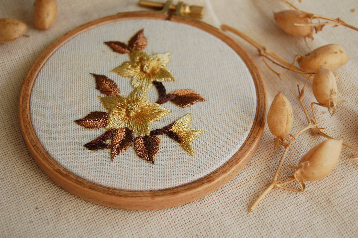 The amber mini golden blooms hoop styled on linen with dried seed pods