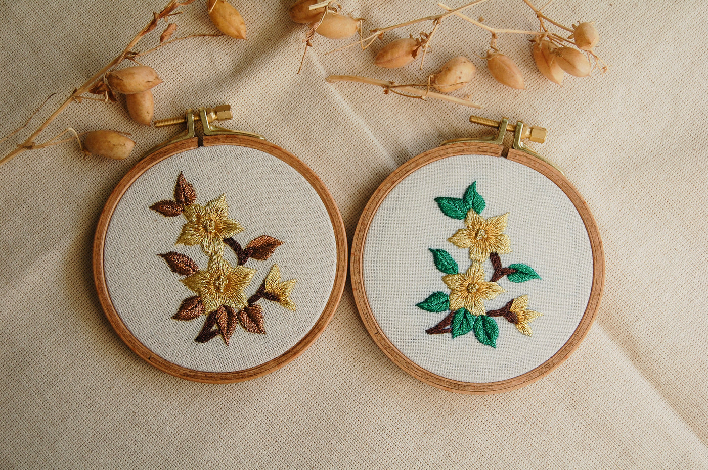 The mini golden blooms design stitched in two colourways, jade and amber, in small wooden hoops