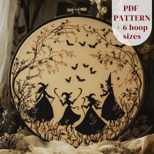 Embroidery hoop with Halloween-themed design of witches and bats on a neutral background.